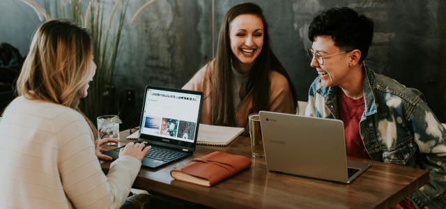 three people sitting in front of table laughing together by Brooke Cagle courtesy of Unsplash.